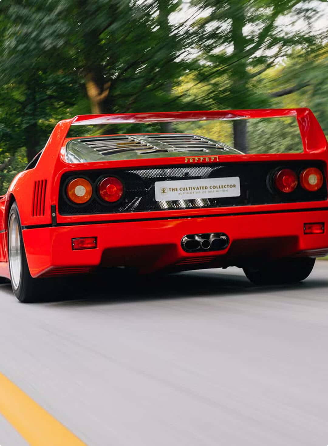 A red Ferrari sports car speeds down a scenic road, showcasing its sleek design and vibrant color