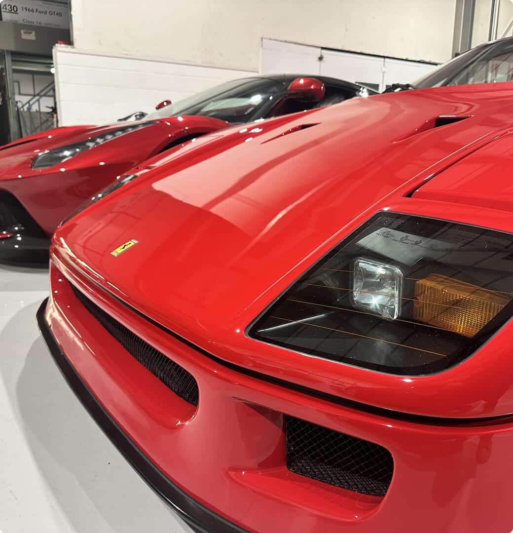 A vibrant red sports car is parked in a well-lit garage, highlighting its modern features and shiny finish