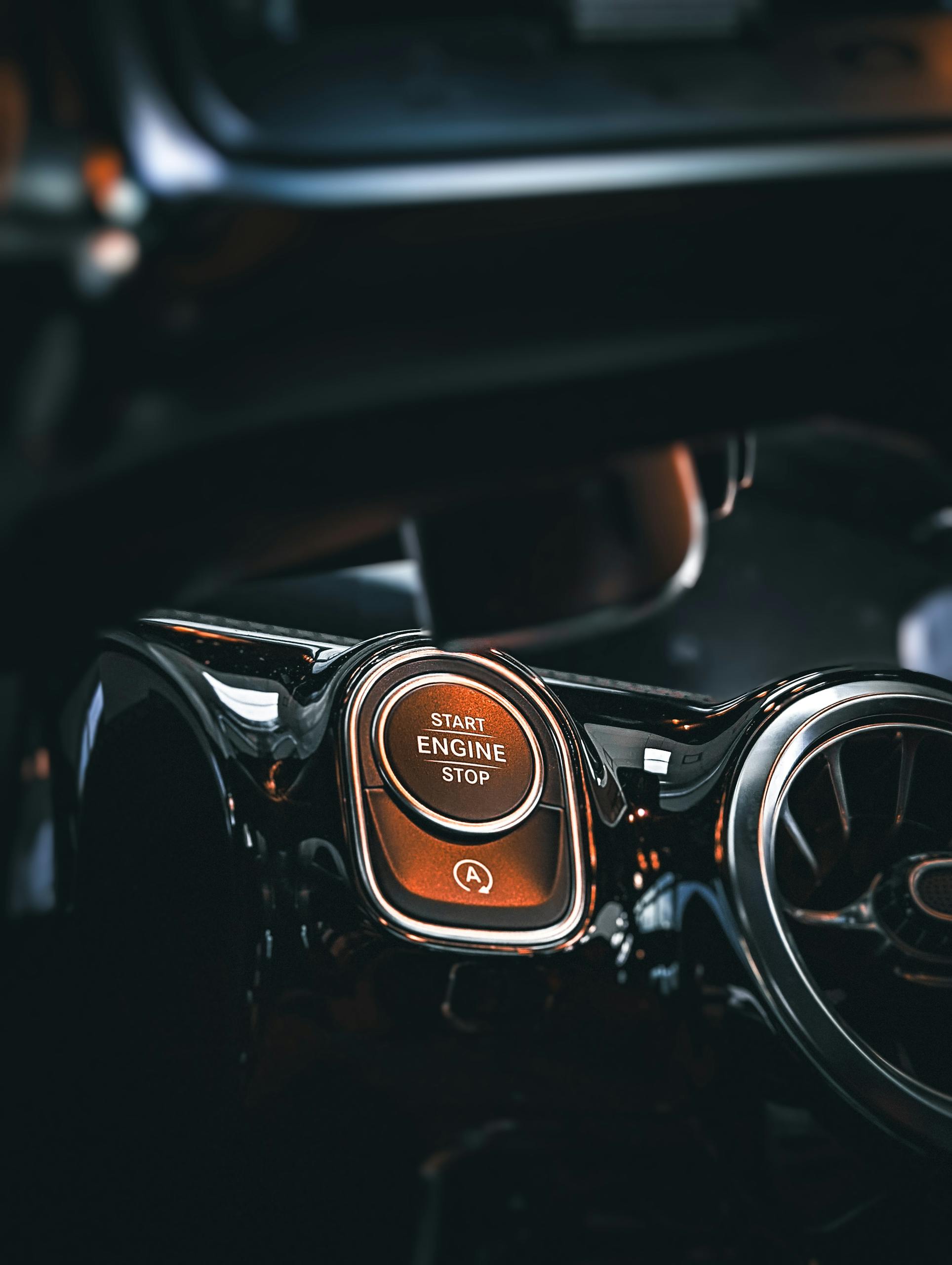 Close-up of a luxury car's start engine stop button on a sleek dashboard.